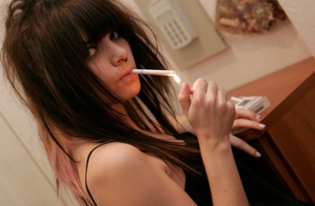 Petite teen Kaira 18 smokes a cigarette while getting naked in her bedroom