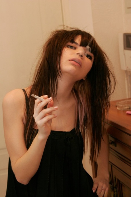 Petite teen Kaira 18 smokes a cigarette while getting naked in her bedroom